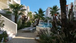 a courtyard with palm trees and a swimming pool at VELORA STAYS Florinas in Lido di Jesolo