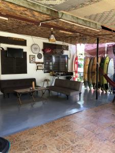 a room with a couch and a table and some surfboards at Surf house langkawi in Pulau Tepur