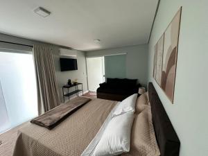 a bedroom with a large bed and a television at Aconchego do Lago in Espirito Santo Do Pinhal