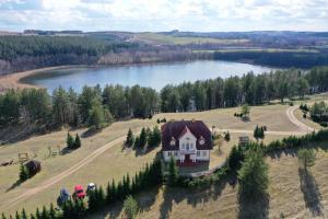 an aerial view of a house on a field next to a lake at Dworek Zielone Wzgórza Nad Jeziorem in Postawele
