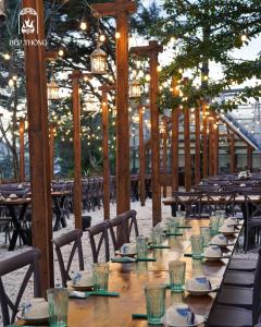 a long wooden table with plates and glasses on it at Bếp Thông home in Xuan An