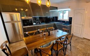 a kitchen with a wooden table with chairs and a refrigerator at Zen Villa Porto Molo in Ávdhira