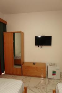 a bedroom with a tv on the wall and a dresser at Guest House RosAmado in São Filipe