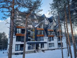 a large white building in the snow with trees at MONA Apartman - Šumska Oaza in Divčibare