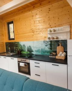 a kitchen with white cabinets and a blue couch at Panorama Pool Hills in Ledinci
