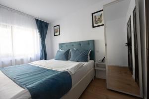 a bedroom with a large bed with a blue headboard at 3 Baneasa Airport in Bucharest