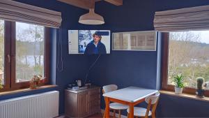 a blue room with a table and a tv on the wall at Mrągowo Pokoje nad jeziorem i Apartament rodzinny in Mrągowo