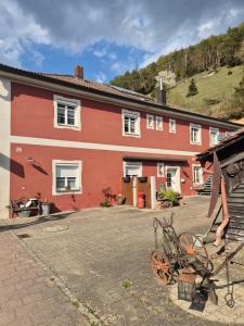 a man standing in front of a red building with a bike at Ferienwohnung Meyer in Kinding