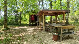 a picnic table and a wooden shelter in the woods at Cabane perchée in Mongauzy
