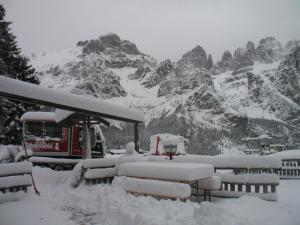 a snow covered mountain in front of a gas station at Rifugio La Montanara in Molveno