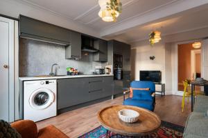 a kitchen and living room with a washing machine and a table at Stylish Harbourfront Apartment in Torquay +12 photos