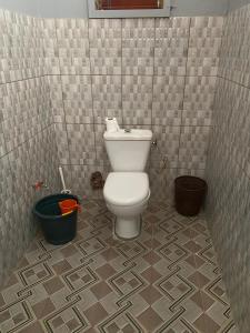 a bathroom with a toilet in a tiled room at Campement Emanaye in Oussouye