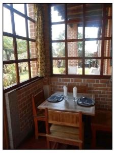 a table in a room with a brick wall and windows at Hotel Anjara in Ambositra