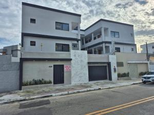 a white building with a car parked in front of it at Apart Suítes Praia Do Morro 5 a 7 dias e Barato in Guarapari