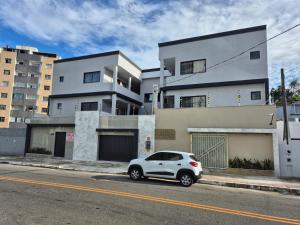 a white car parked in front of a building at Suites Casal Com AR Semanal ou 7 dias E BARATO in Guarapari