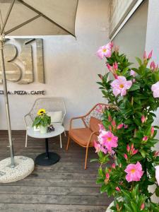 eine Terrasse mit rosa Blumen, einem Tisch und einem Sonnenschirm in der Unterkunft Hotel Marolda in Sirmione
