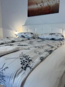 ein weißes Bett mit einer blau-weißen Bettdecke und Kissen in der Unterkunft Nedi's Nest - Cozy Countryside Retreat Under Palmtrees in Dutovlje