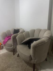 a room with three chairs and a cat laying on a couch at The sun Pyramids View in Cairo