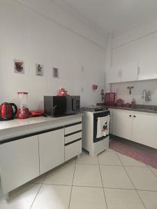 a white kitchen with a stove and a microwave at Morada Vermelha in Vitória da Conquista +8 photos