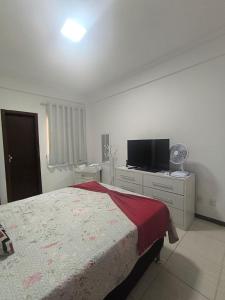 a bedroom with a bed and a flat screen tv at Morada Vermelha in Vitória da Conquista
