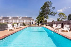 a swimming pool with lounge chairs and a house at Baymont by Wyndham Albany at Albany Mall in Albany
