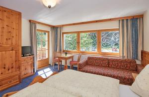 a bedroom with a bed and a couch and a tv at Haus Traudl in Filzmoos