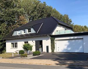 a white house with a large garage at Harz-Fewo Weitsicht, modern & ruhig mit 2 Balkonen, Jura Kaffeevollautomat, Kaminofen, Gäste mit Hund willkommen in Bad Harzburg