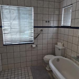 a bathroom with a toilet and a tub and a window at Kleingeluk Guest Cottages in Louis Trichardt
