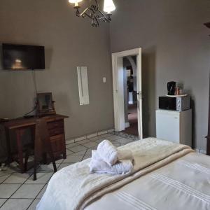 a bedroom with a bed and a desk and a television at Kleingeluk Guest Cottages in Louis Trichardt