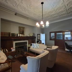 a living room with chairs and a couch and a fireplace at Kleingeluk Guest Cottages in Louis Trichardt