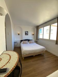 a bedroom with a bed and a table in it at Hôtel L'Oustaou in Le Lavandou