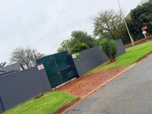 a fence with a palm tree next to a street at The Stillhouse Guest House in Edenvale