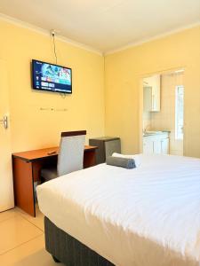 a bedroom with a bed and a desk and a television at The Stillhouse Guest House in Edenvale +5 photos