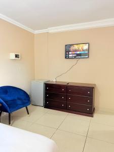 a bedroom with a dresser and a tv on the wall at The Stillhouse Guest House in Edenvale