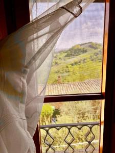 a window with a white curtain and a view at Casa del Sole in Gambassi Terme