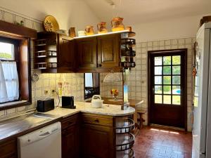 a kitchen with wooden cabinets and a sink at Casa de praia com piscina in Árvore