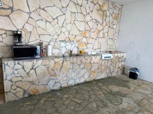 a stone wall with a counter with a microwave on it at Del Mar Beach House in Nimá