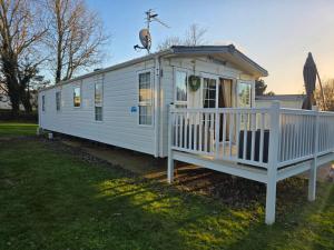 a white tiny house with a porch on the grass at Westwood Hide Away in Allhallows