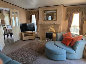 a living room with a blue chair and a television at Westwood Hide Away in Allhallows