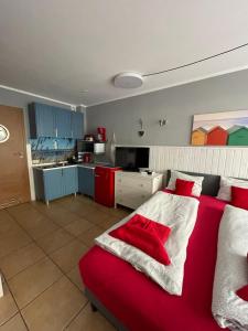 a bedroom with a red bed and a kitchen at Villa Park & Plaża in Świnoujście