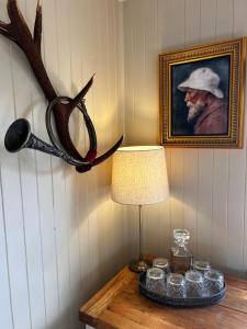a table with a lamp and a picture of a man at Stunning country home with private wellness Spa in Strachur