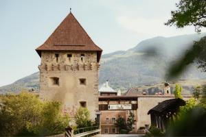 a building with a tower and a mountain in the background at Venostis in Prato allo Stelvio