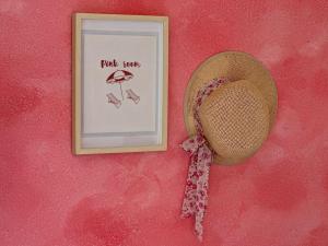 a straw hat and a picture on a pink wall at Saleto Apartma in Jagodje +27 photos