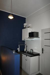 a kitchen with white cabinets and a blue wall at Izba Kupiecka in Bystrzyca Kłodzka