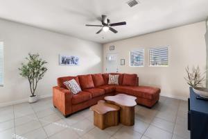 a living room with a brown couch and a ceiling fan at Stylish 4BR Escape Open Layout TVs in Every Room in El Paso