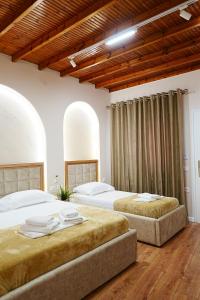 two beds in a bedroom with wooden ceilings at Arial Trinity Suites in Vlorë