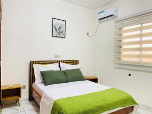 a bedroom with a bed with a green blanket on it at Rieti Yamehome in Yaoundé