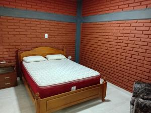 a bed in a room with a red brick wall at Dptos Edu in Malargüe
