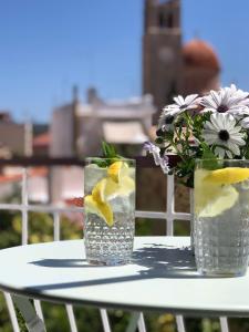 two glasses of water and a vase of flowers on a table at Oikiaegina in Egina