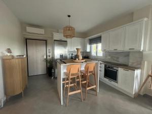 a kitchen with white cabinets and a island with stools at Coral Nikiti Apartments I in Nikiti